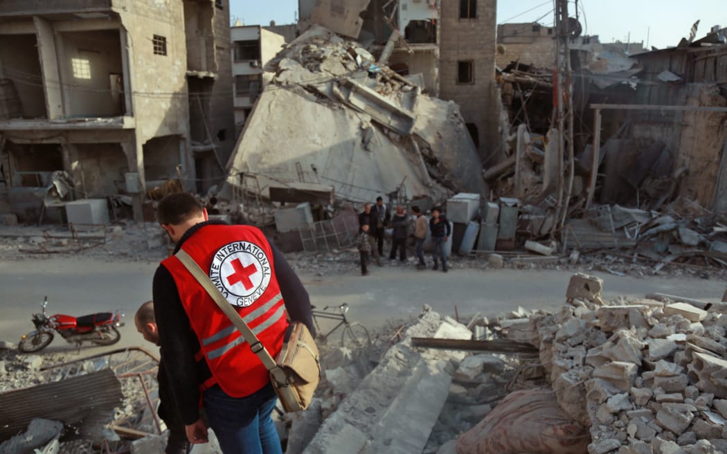 A International Red Cross volunteer stands above the rubble of a destroyed building in Douma, Eastern Ghouta, Syria on March 5, 2018.