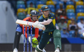 Australia's David Warner, right, hits as England's captain Jos Buttler watches during the ICC men's Twenty20 World Cup 2024 group B cricket match between Australia and England at Kensington Oval in Bridgetown, Barbados, on 8 June 2024. (Photo by Randy Brooks / AFP)
