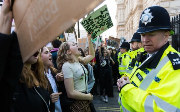 Police watch students in the London as they protest over climate change.