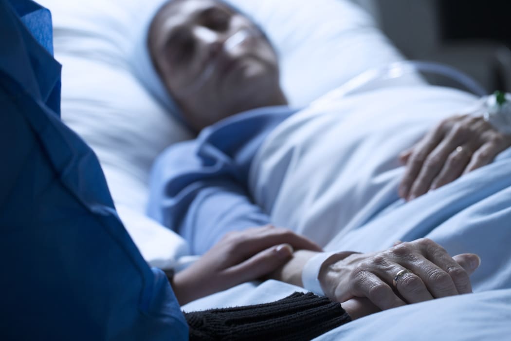 Young woman in hospice care, holding hands in hospital.