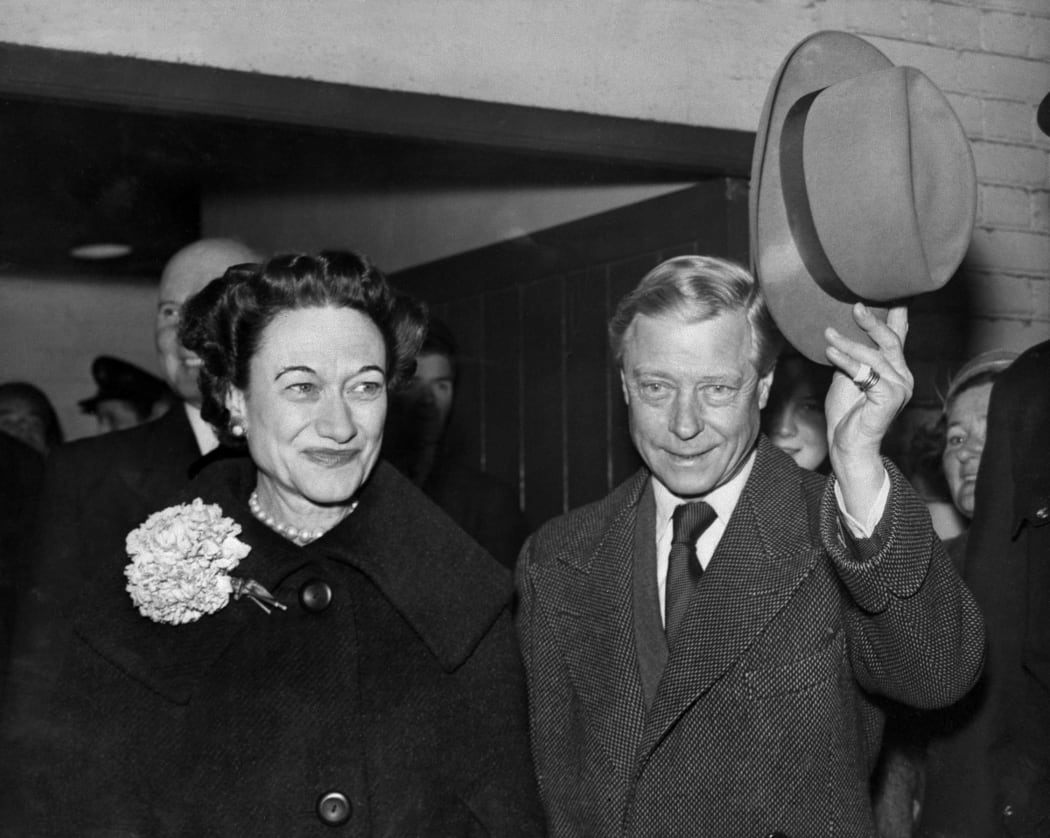 Edward, Duke of Windsor (R), with his wife the Duchess Wallis of Windsor, waves his hat to the welcoming crowd as they arrive at Victoria Station in London, from Paris, 13 November 1956. This is their first visit together to Britain since 1953.