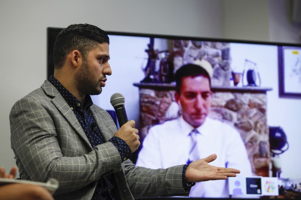 David Miranda, left, looks on as his partner Glenn Greenwald speaks via video link during a Russian discussion about the right to privacy.