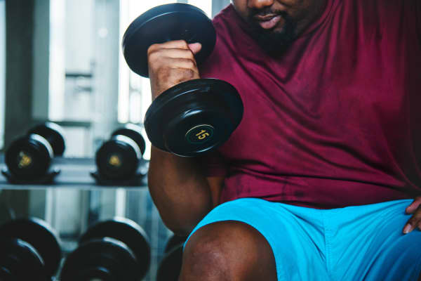 A man lifts a dumbbell in a gym.