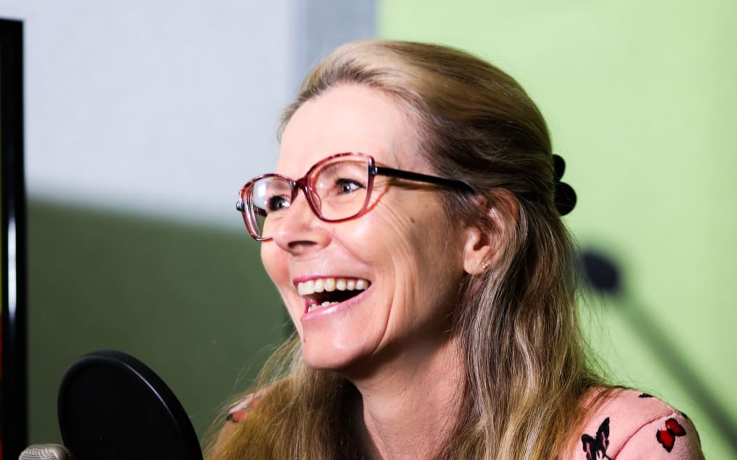Image of woman smiking with recording gear in front of her.