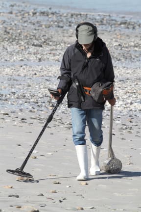 Man with metal detector on beach.