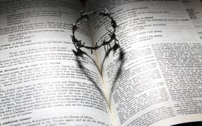 Bible with miniature crown of thorns casting a heart-shaped shadow