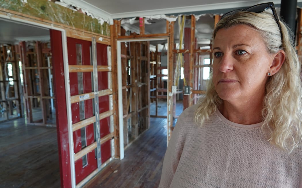 Lynley Halpin stands in the shell of her family home, unsure of its future.