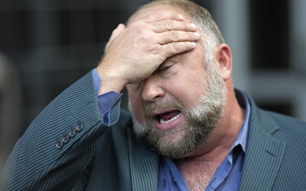 Alex Jones wipes his forehead as he speaks to media after arriving at the federal courthouse for a hearing in front of a bankruptcy judge Friday, 14 June, 2024, in Houston.