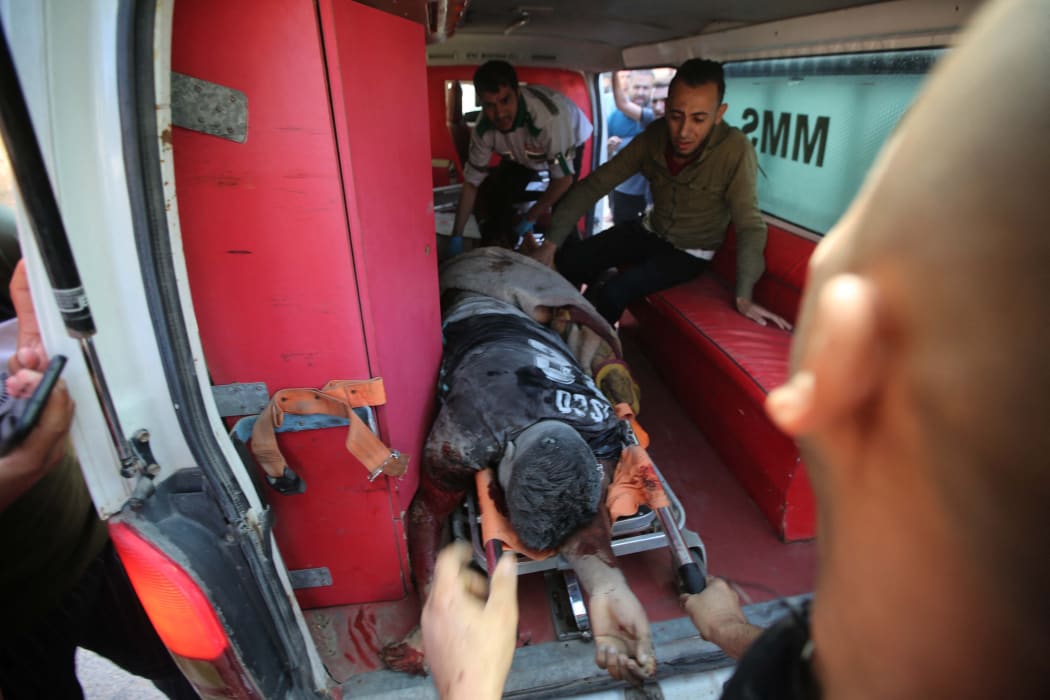 Health team members and civilians carry a wounded man to an ambulance after Israeli fighter jets conducted airstrikes towards a building in Al-Bureyc refugee camp of Gaza Strip, Gaza on May 13, 2021.