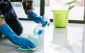 Husband housekeeping and cleaning concept, Happy young man in blue rubber gloves wiping dust using a spray and a duster while cleaning on floor at home.