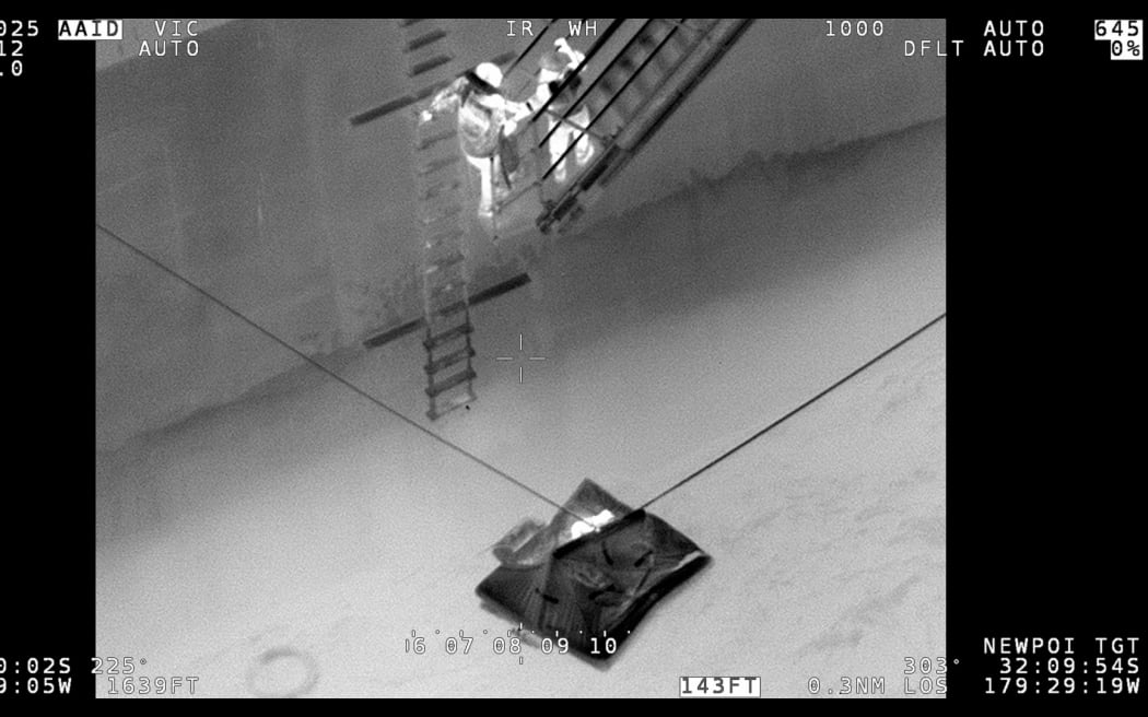 A life raft alongside a merchant vessel.