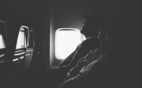 Black and white image of people sleeping on a plane