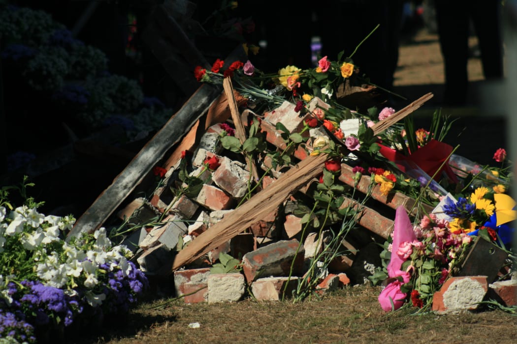 Flowers are placed on the rubble of a building damaged in the quake during a national memorial service held in Christchurch on March 18, 2011 in memory of the earthquake on February 22nd.