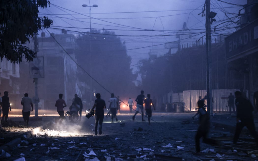 EDITORS NOTE: Graphic content / People run along a debris-strewn street following Israeli air strikes in Gaza City on October 7, 2023. Palestinian militants have begun a "war" against Israel which they infiltrated by air, sea and land from the blockaded Gaza Strip, Israeli officials said, a major escalation in the Israeli-Palestinian conflict. (Photo by Mohammed ABED / AFP)