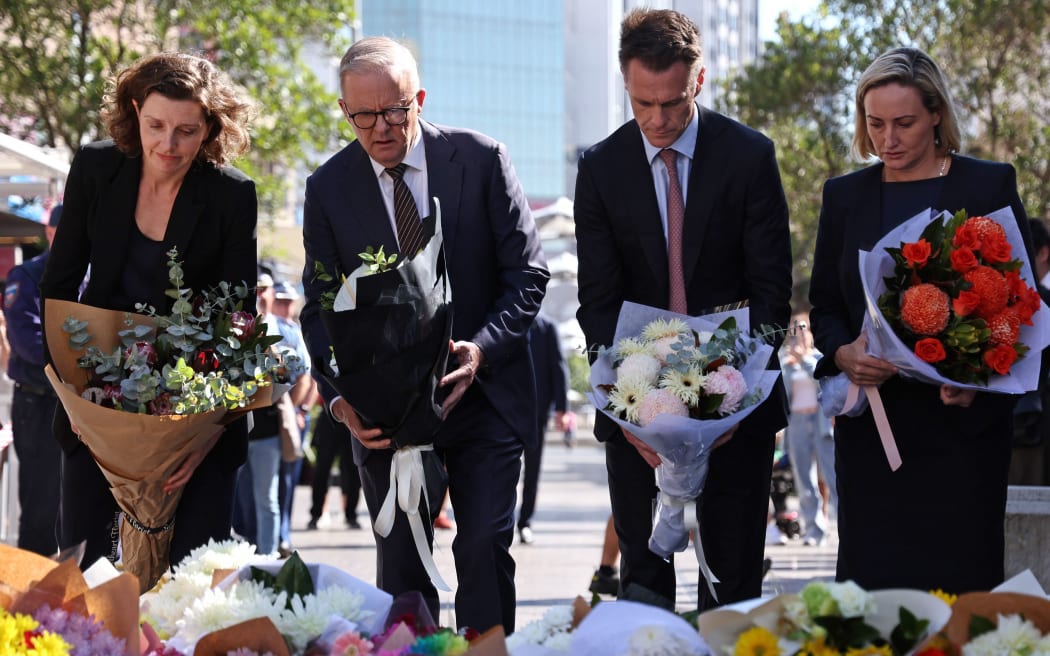 Australian Prime Minister Anthony Albanese (2nd L), New South Wales Premier Chris Minns (2nd R) and federal member of parliament Allegra Spender (L) leave flowers outside the Westfield Bondi Junction shopping mall in Sydney on April 14, 2024, the day after a 40-year-old knifeman with mental illness roamed the packed shopping centre killing six people and seriously wounding a dozen others. (Photo by DAVID GRAY / AFP)