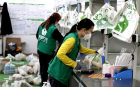 Staff members of the online grocery platform Meituan Maicai sort and pack ordered groceries in east China's Shanghai, April 12, 2022.