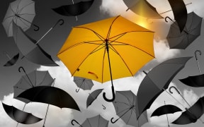 Yellow umbrella seen vividly against background of black umbrellas