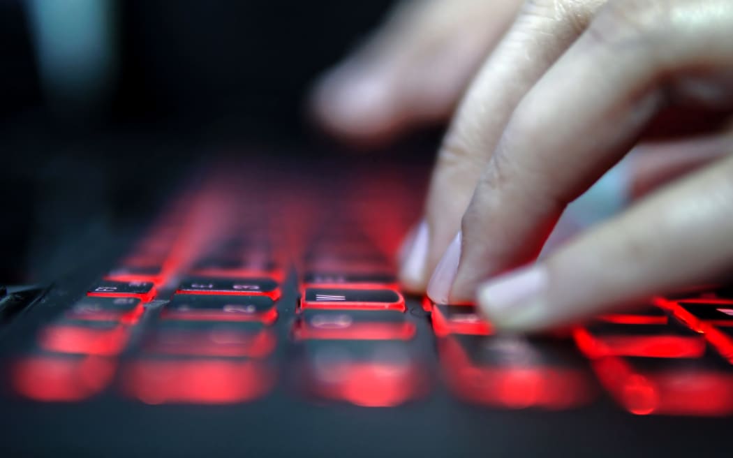 Teenage Hacker Girl Attacks Corporate Servers in Dark, Typing on Red Lit Laptop Keyboard. Room is Dark