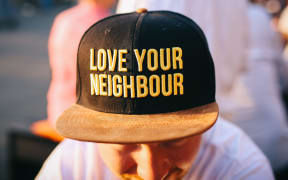 man in 'love your neighbour' cap