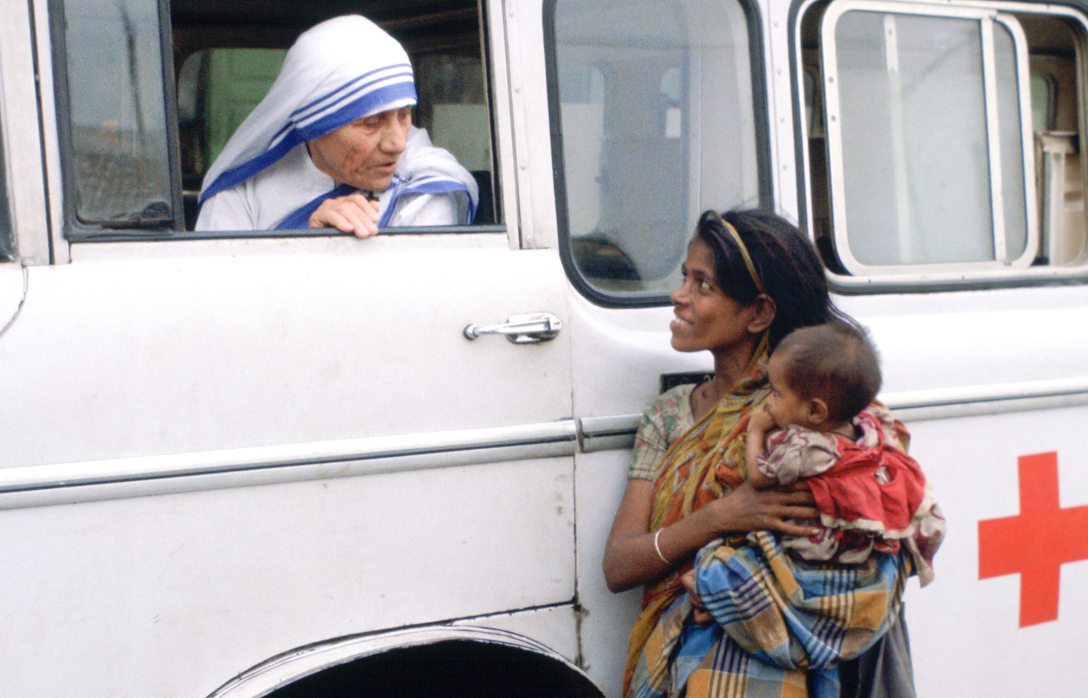 Mother Teresa talking with a poor woman and her child from a Red Cross minibus in Calcutta, India.