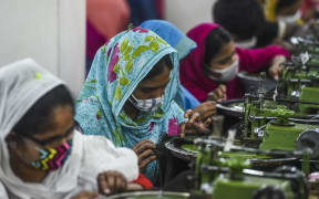 Labourers wearing facemasks work in a garment factory during a government-imposed lockdown as a preventative measure against the COVID-19 coronavirus in Asulia, on the outskirts of Dhaka on April 7, 2020.