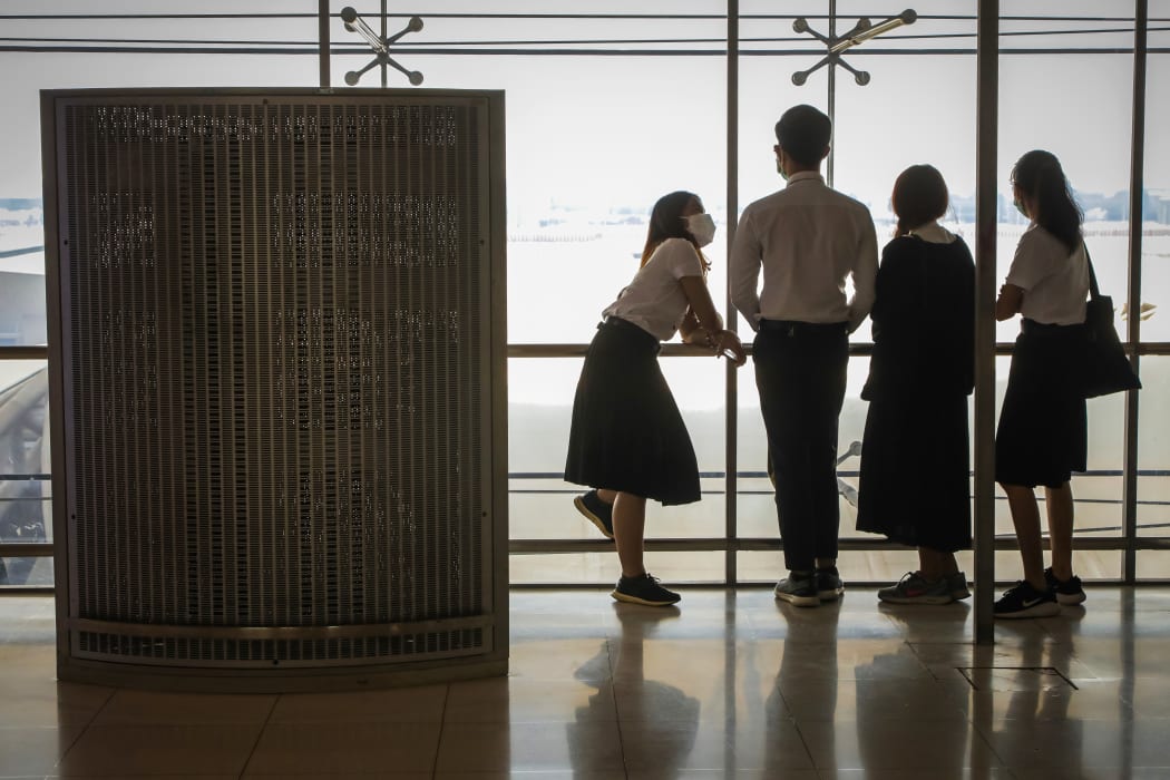 Students wearing protective face masks stand overlooking the runway in a viewing deck at Suvarnabhumi Airport in Bangkok on February 21, 2020.