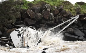 A damaged yacht that was swept away by the waves rests at Point Danger on the southern end of the Gold Coast on March 7, 2025. Violent winds toppled power lines on March 7 as Tropical Cyclone Alfred inched towards Australia's eastern coast, sparking evacuation orders and leaving more than 50,000 homes without electricity. (Photo by David GRAY / AFP)