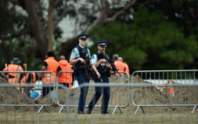 Police patrol a cemetery as workers prepare grave sites.