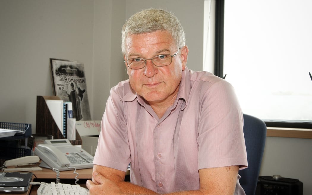 Photo of Peter Lineham sitting at his desk, leaning forward.