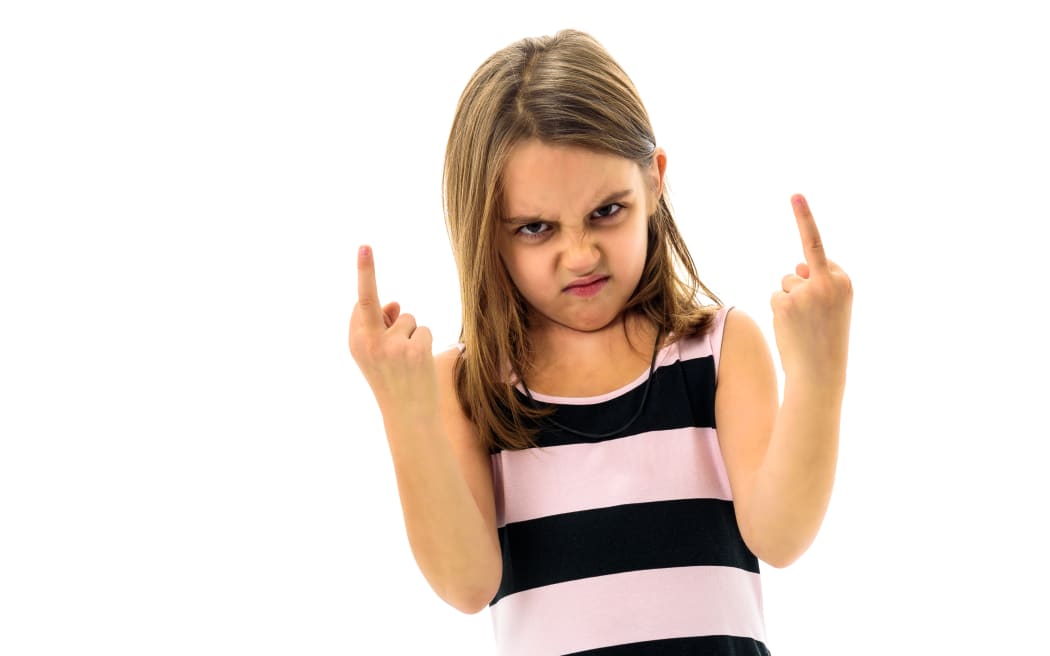 Little young girl is angry, mad, disobedient with bad behaviour. Children making the act of insubordination and disobedience, yelling, flipping off, showing the middle finger. Act of giving the finger.