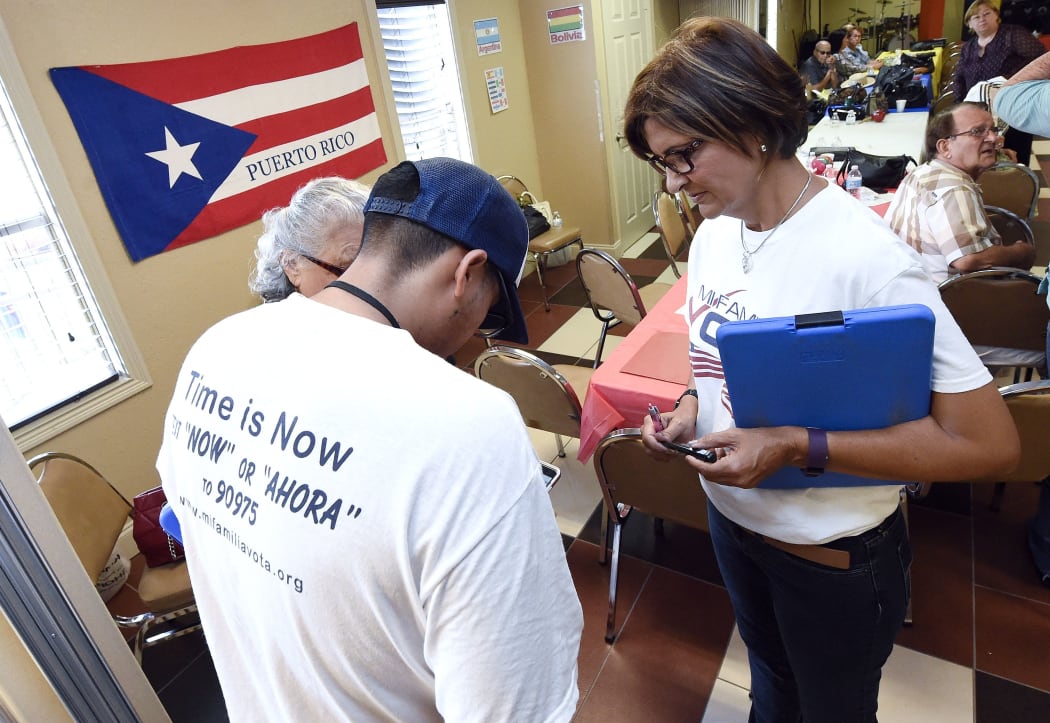 "Mi Famila Vota" (My Family Votes) representative Jose Castellanos (L) and Naloy Zapata (R) register people to vote during a Hispanic Heritage Celebration breakfast at the Kingdom of God Church in Orlando, Florida
