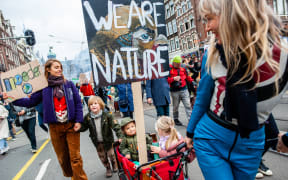 Two women transporting their children in a cargo bike during a massive Climate march organized in Amsterdam, on 6 November  2021.