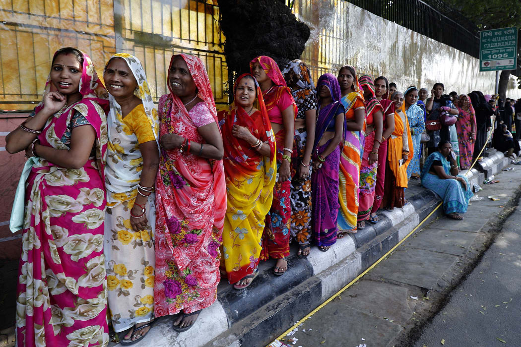 Indian women stand in a queue to deposit and exchange discontinued rupees outside a bank in Jaipur, India.