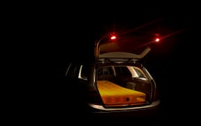 A mattress in the back of a station wagon at night to illustrate people sleeping in cars or vans.
