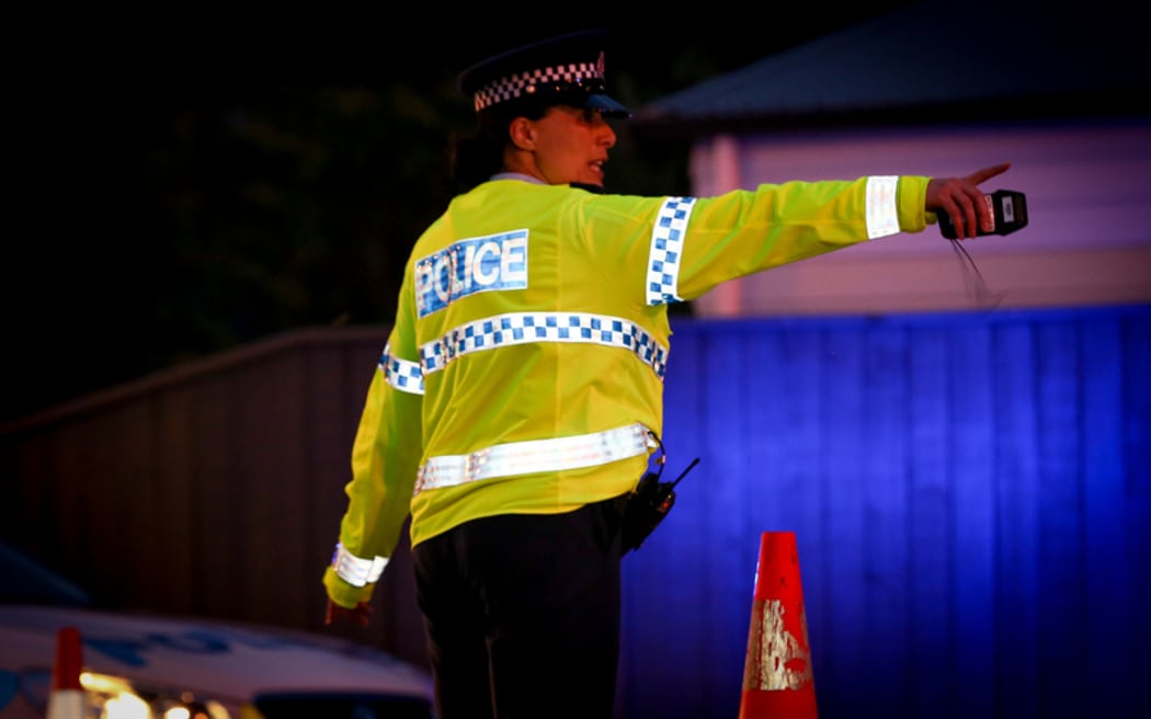 A police officer directing traffic at an alcohol check point.