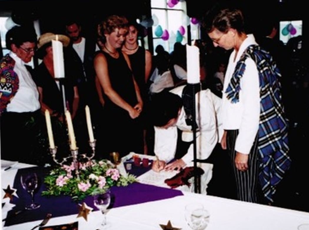 An image of the couple signing the marriage register.