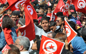 Tunisians wave their national flag and chant slogans during a march against extremism outside Tunis' Bardo Museum.