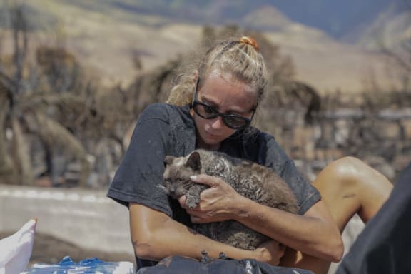 A woman cradles her cat after finding him in the aftermath of a wildfire in Lahaina, western Maui.