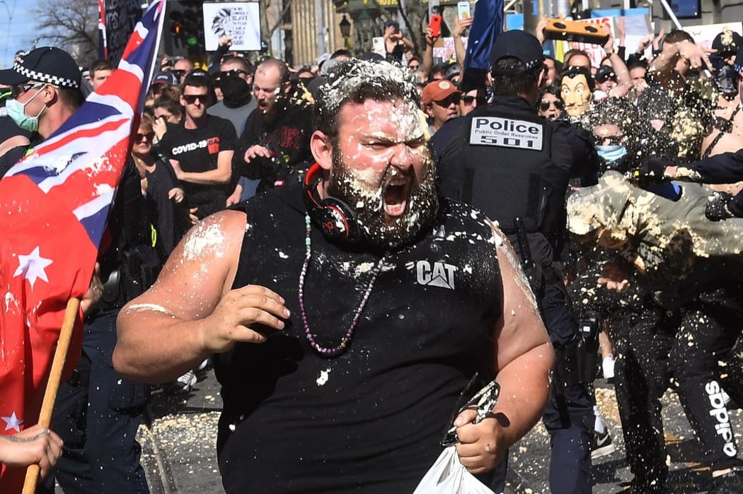 A protester reacts from pepper spray used by police during an anti-lockdown rally in Melbourne today.
