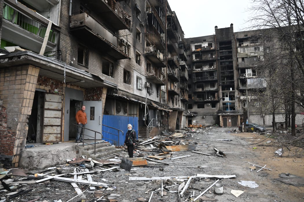 Residents stand outside a residential building damaged by the shelling in Mariupol on 14 April, 2022.