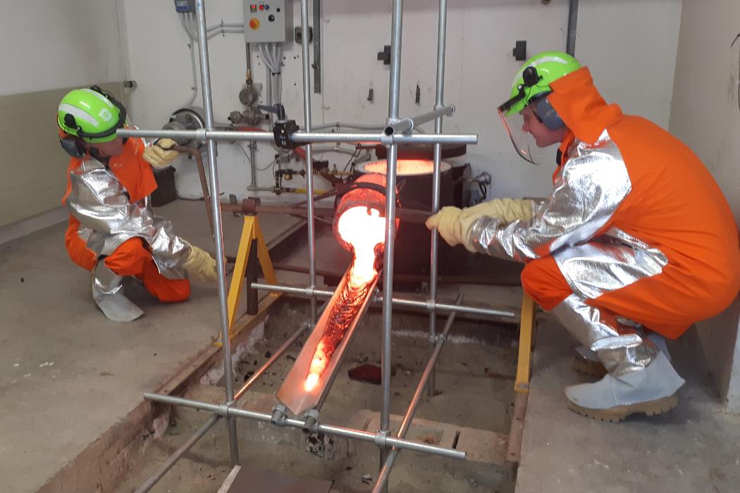 Scientists wearing protective Kevlar clothing pour molten lava from a crucible in the Lava Lab.
