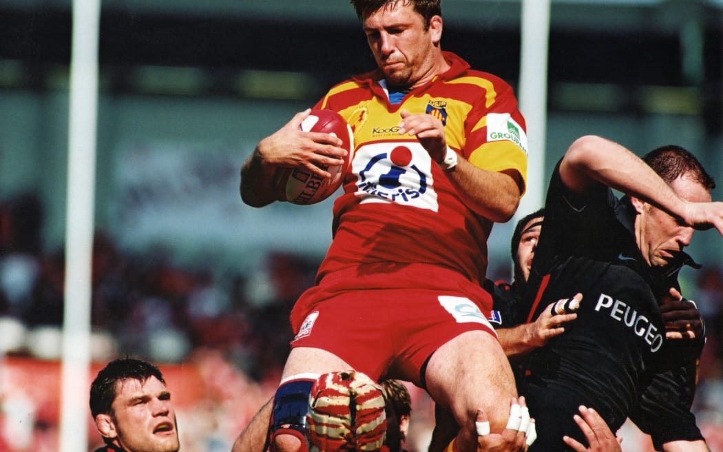 A photo of Fair Game Host, John Daniell being raised up for a lift during a rugby game. He was playing for the French team, Perpignan in 2001. This match was against Toulouse.