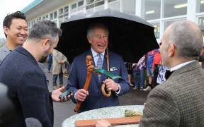 Britain's Prince Charles, Prince of Wales is given a gift as he leaves Critical Design at Wesley Intermediate School in Auckland on November 18, 2019. The Prince of Wales and Duchess of Cornwall are on an 8-day tour of New Zealand. (Photo by MICHAEL BRADLEY / AFP)