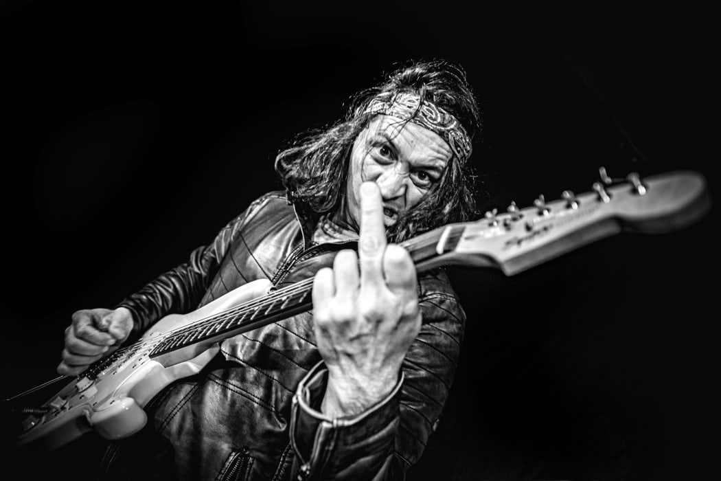 Aaron Tokona flips the bird while holding his guitar in this iconic photo by Alexander Hallag