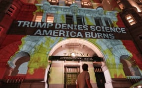 Activists project flames and commentary on the side of the Trump International Hotel in protest of President Donald Trump's response to science and climate change.