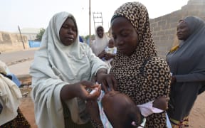 A volunteer health worker tries to immunise a child during a vaccination campaign in north-west Nigeria