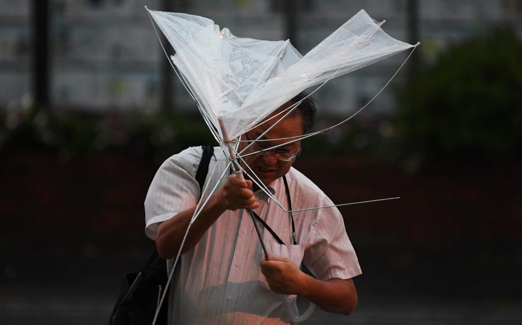 A man with an umbrella crosses a street early morning under the rain as a typhoon hits Tokyo on September 9, 2019.
