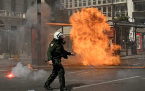A Greek riot policeman walks past an exploded molotov during a demonstration, near the Greek parliament in Athens, on March 5, 2023, following the deadly accident near the city of Larissa, where 57 people, mainly students lost their lives. - Violent clashes broke out between police and protesters outside the Greek parliament in Athens on March 5 as thousands attended a rally following the nation's worst rail disaster that killed 57, AFP reporters saw. (Photo by Louisa GOULIAMAKI / AFP)
