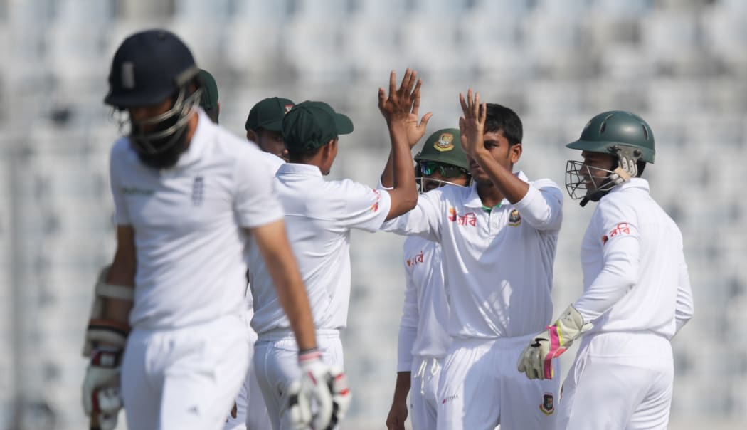 Bangladesh's Mehedi Hasan receives high fives from teammates after taking the wicket of England's Moeen Ali