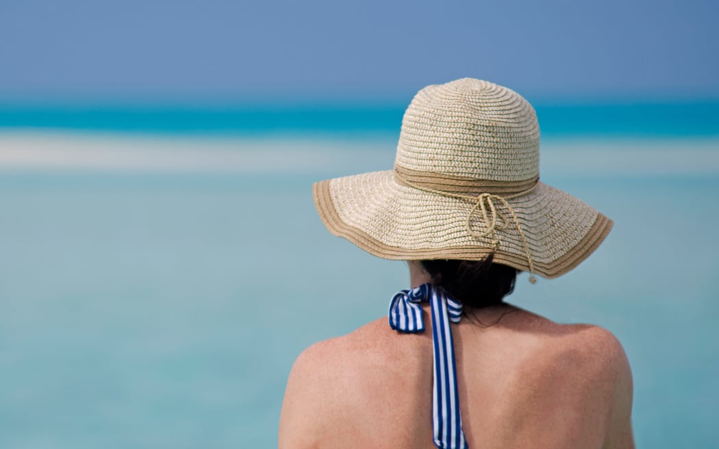 Happy woman enjoying beach relaxing during travel vacation on tropical island in Aitutaki lagoon, Cook Islands.
